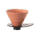 Terracotta-colored funnel-shaped object on a black stand against a white background
