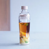 Clear bottle with a fruit-infused drink on a light blue background