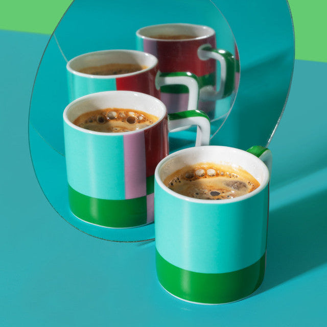 Colorful coffee cups with a reflective surface on a green and blue gradient background