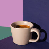 Beige mug with coffee on a multicolored background