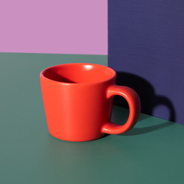 Red mug on a green surface with a purple and blue background