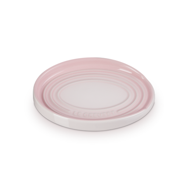 An oval-shaped, shell pink colored stoneware spoon rest with a distinctive three-ring design.