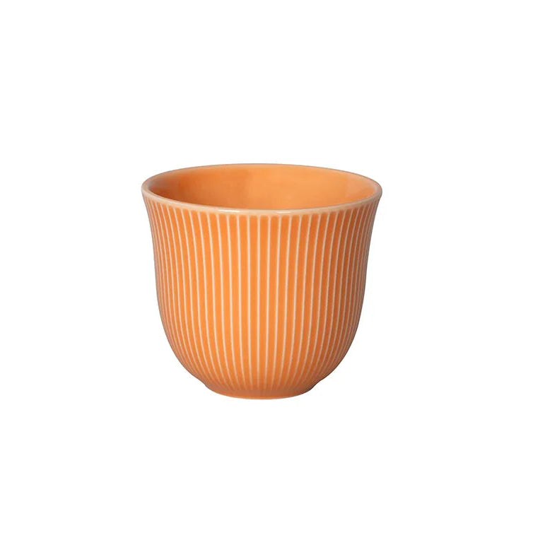 Orange ceramic cup with ribbed texture on a white background
