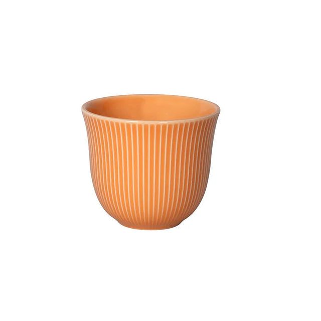 Orange ceramic cup with ribbed texture on a white background