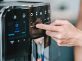 Hand pressing a button on a coffee machine with a blurred background