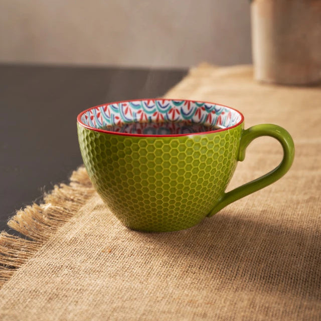 Green textured mug with a colorful interior on a wooden surface.