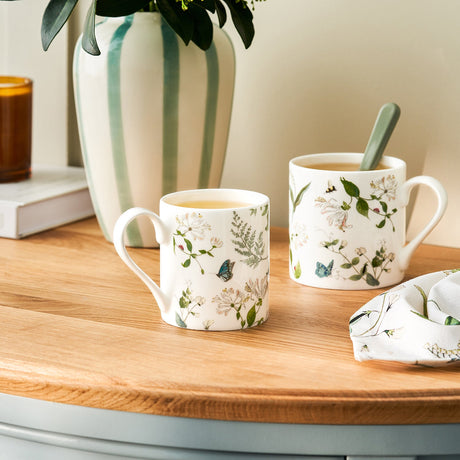 Sophie Allport Wild Floral mugs on a wooden kitchen worktop beside a vase and matching textiles