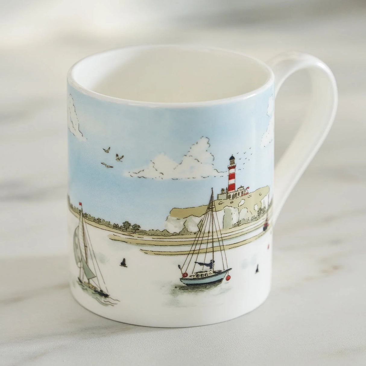 Mug with a nautical design featuring a lighthouse and boats on a light blue background.