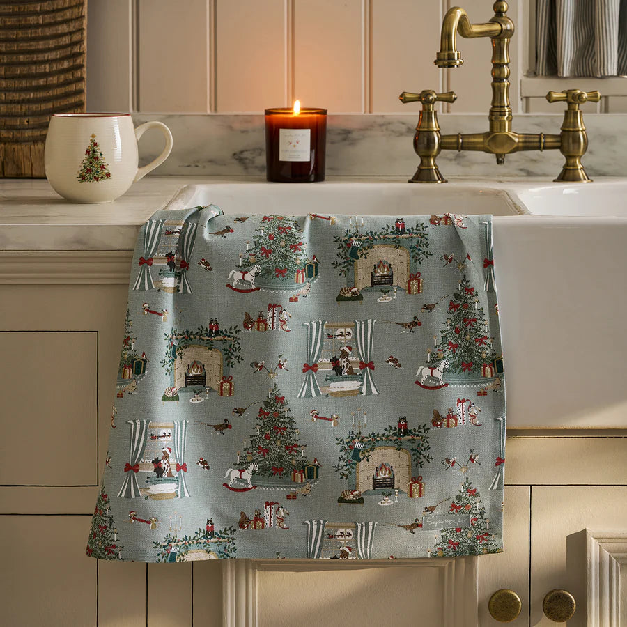Decorative towel with Christmas pattern on a kitchen counter with a mug and candle.