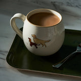 White mug with dog illustrations on a green tray with a spoon