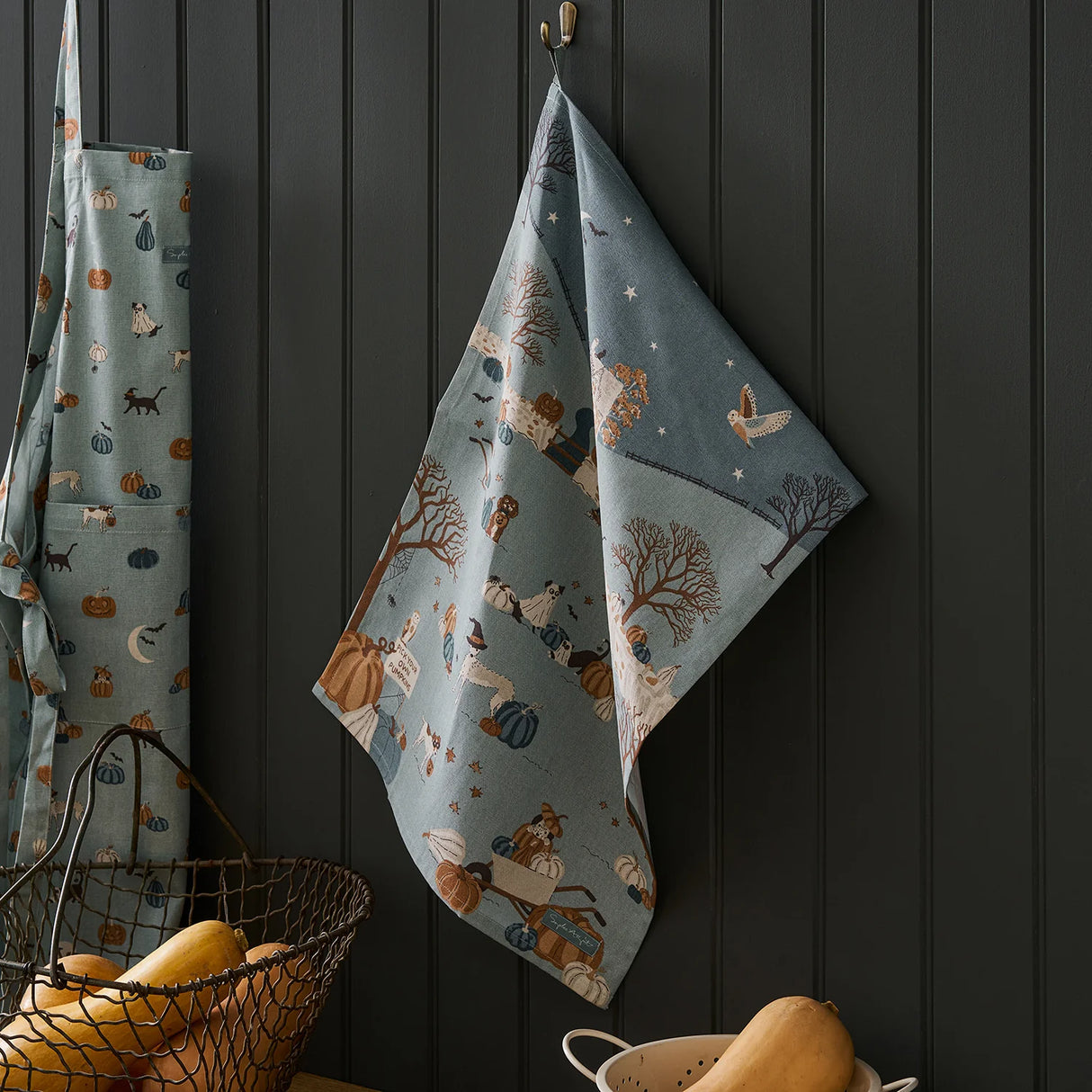 Decorative kitchen towel with animal pattern hanging on a dark wooden wall.