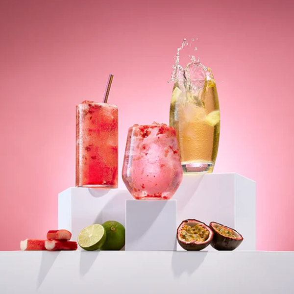 Three colorful cocktails on a white surface with a pink background