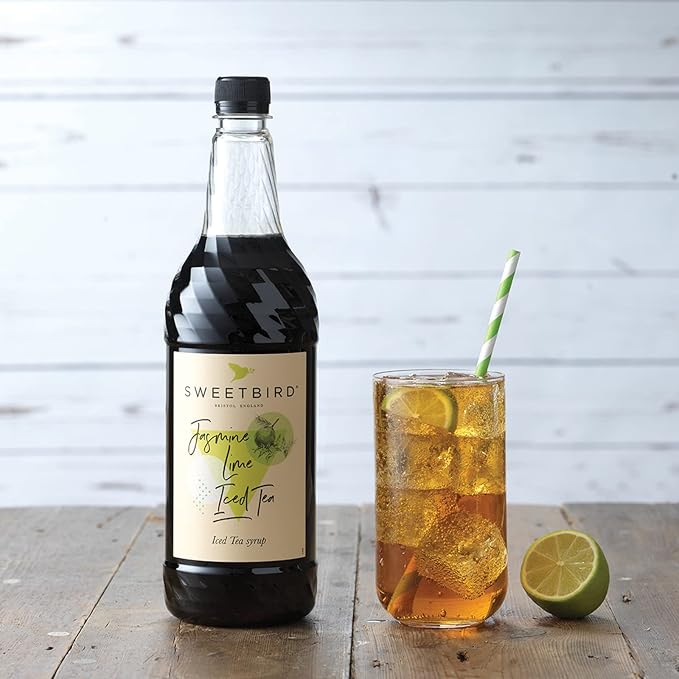 Bottle of Sweetbird Iced Tea syrup with a glass of iced tea on a wooden surface.