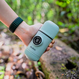 Hand holding a light blue travel mug with a blurred natural background