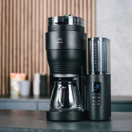 Black coffee maker with a digital display on a kitchen counter.