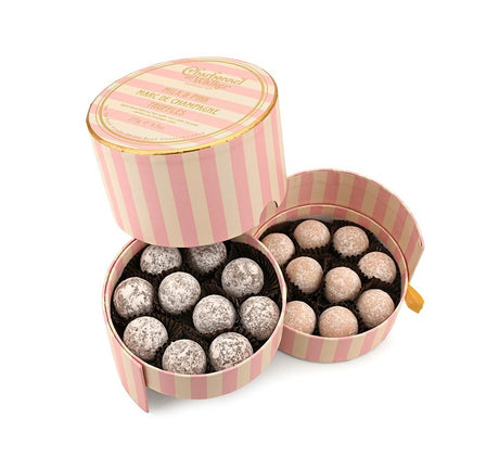 Open pink striped box containing chocolate truffles on a white background