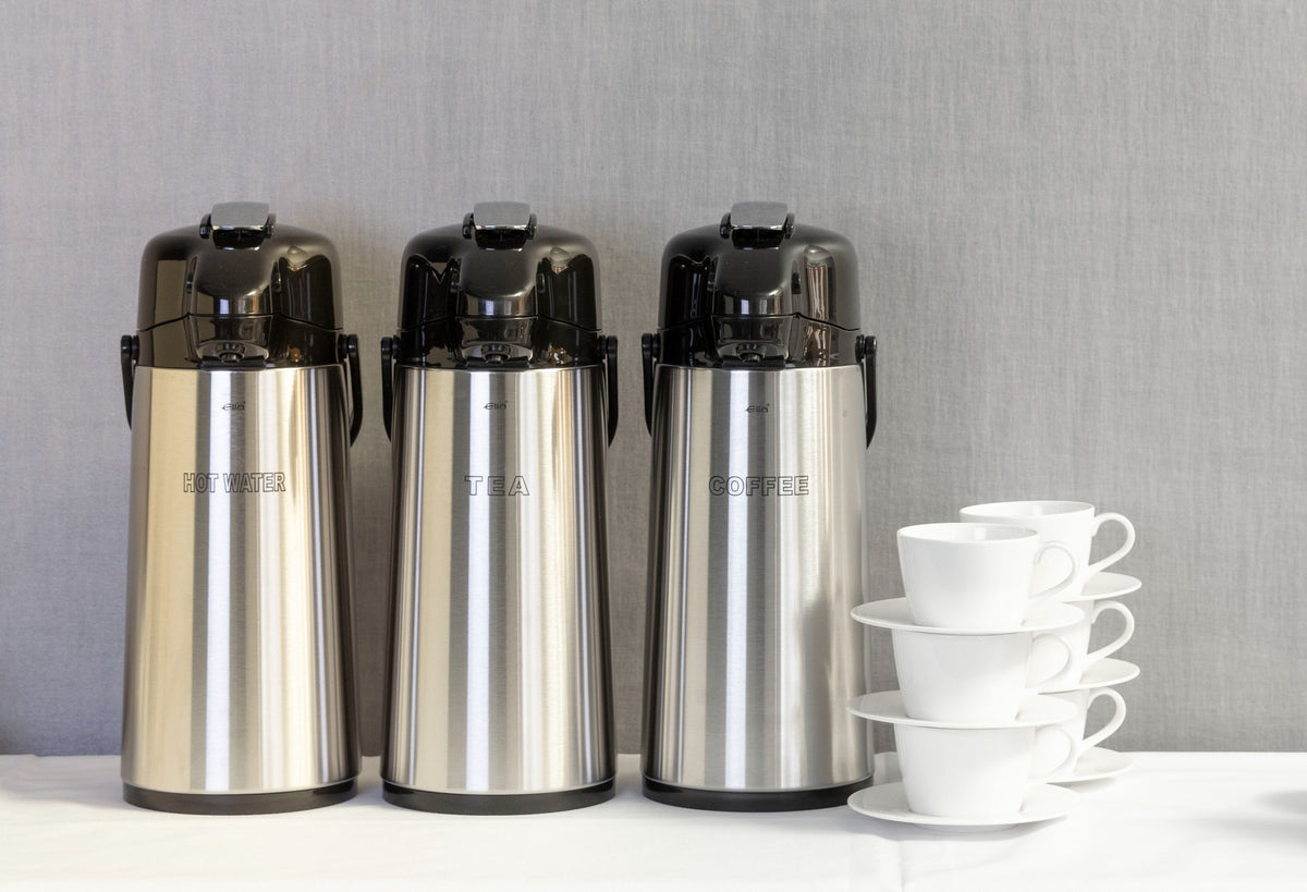 Elia BGL stainless steel airpots arranged beside white cups at a beverage serving station