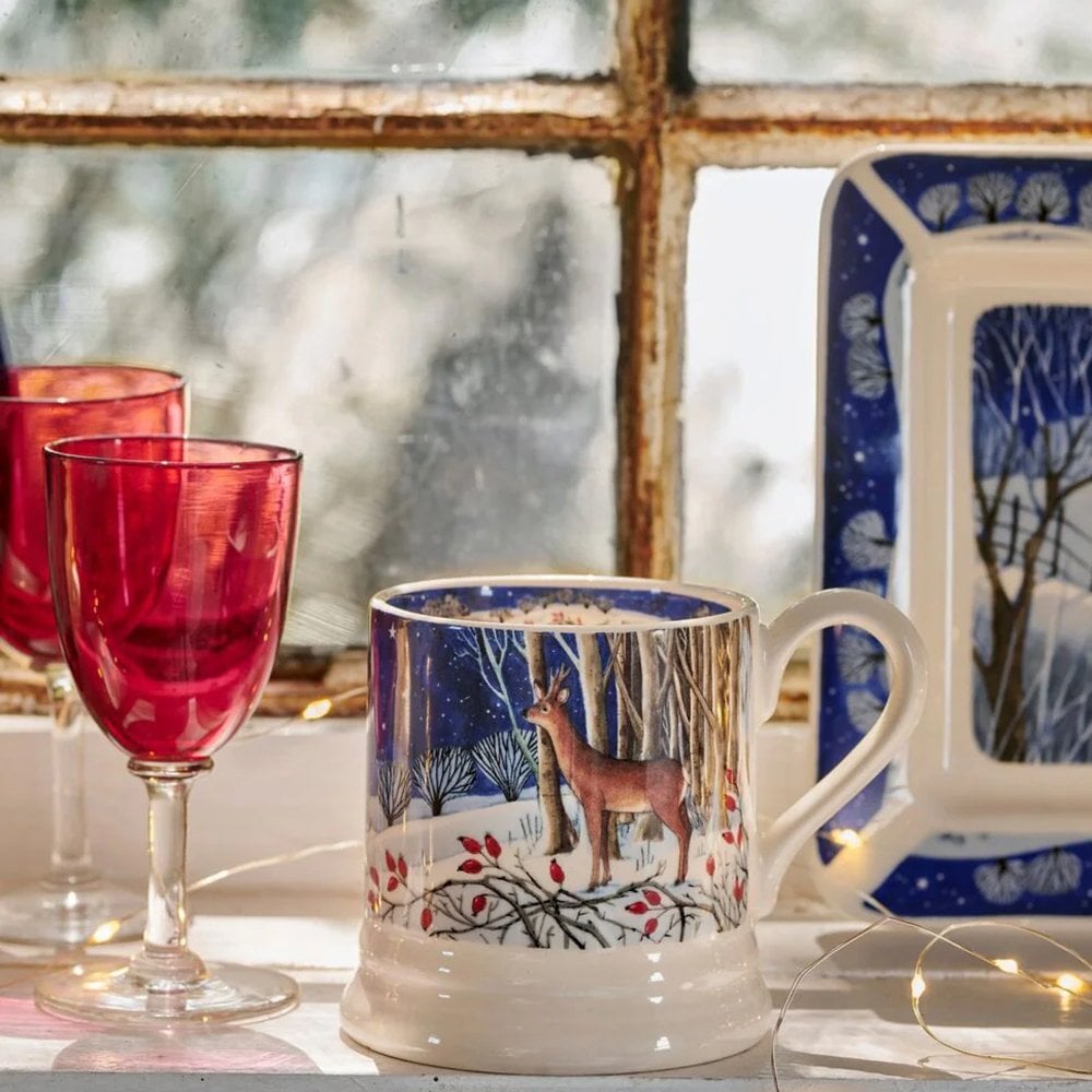 Mug with deer design on a table with red glasses and a blurred window background