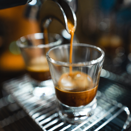 Espresso being poured into a glass with a blurred background