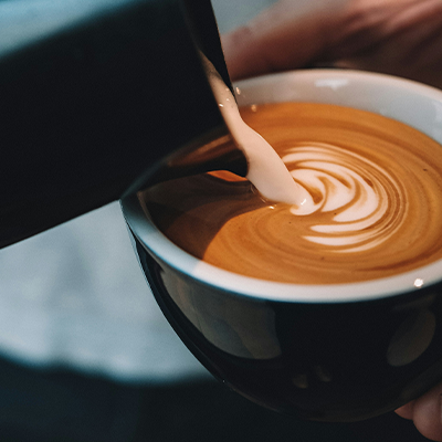 Pouring milk into a cup of coffee to create latte art.