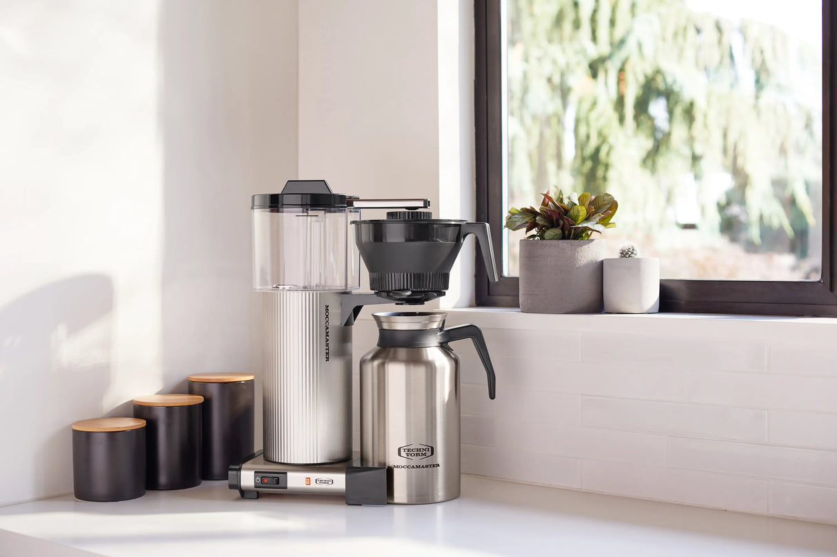 Coffee maker on a kitchen counter with a window in the background