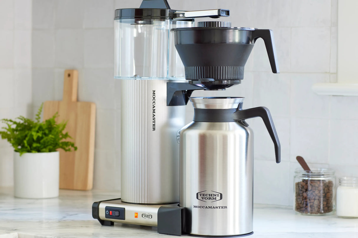 Technivorm Moccamaster coffee maker on a kitchen counter with a thermos.