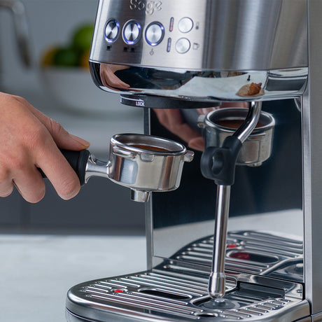 Sage espresso machine with a hand holding a portafilter, ready to make coffee.