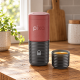 Wacaco Pixapresso Electric Portable Espresso Maker in Tuscan Red on a wooden kitchen table beside a window