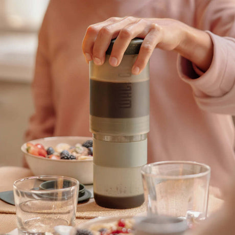 Preparing coffee with a Clay Pink Wacaco Prestina at a kitchen table
