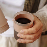 Holding a Clay Pink Wacaco Prestina and its cup of freshly brewed coffee